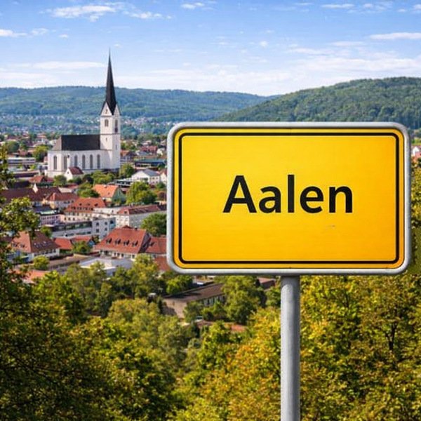 Gelbes Ortsschild Aalen mit Stadt im Hintergrund